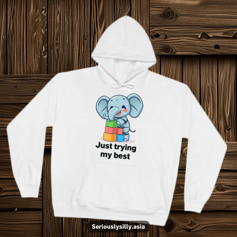 Funny Hoodie featuring a giggling elephant bot balancing a wobbly tower of colorful blocks, warm and humorous.