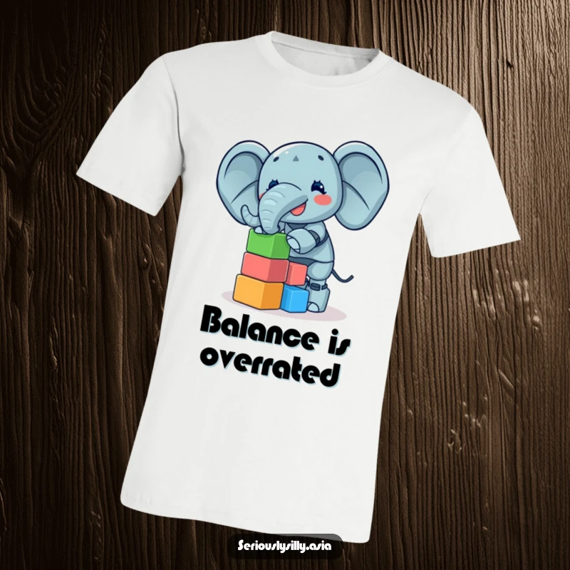 Funny T-Shirt of a giggling elephant bot attempting to stack a high tower of small, vibrant blocks, playful apparel.
